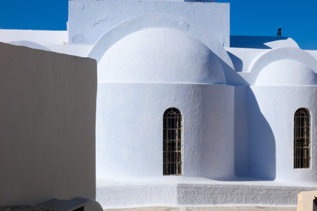 Traditional greek orthodox church with waving flag and blue dome in Santorini, Greeceの写真素材