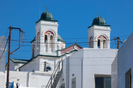 Traditional white church with red doors, byzantine flag, and flag waving in the wind, under a deep blue skyの写真素材