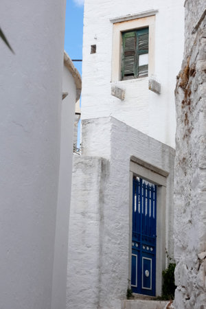 Narrow whitewashed alley with stairs, plants, and traditional architecture in a Greek island villageの写真素材