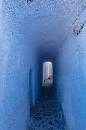 Picturesque alley with narrow tunnel with whitewashed walls, stone pavement, creating a charming Mediterranean atmosphere on the Greek islands, Greeceの写真素材