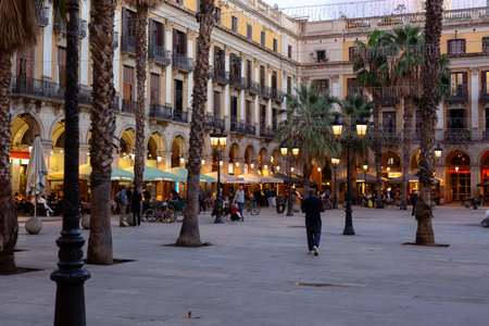 Ornate streetlights illuminating plaÃ§a reial at dusk with tourists and locals enjoying the...