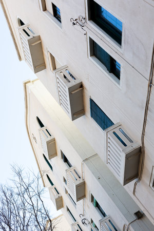 Architectural view of a narrow alley separating buildings with balconies and electrical wires,...