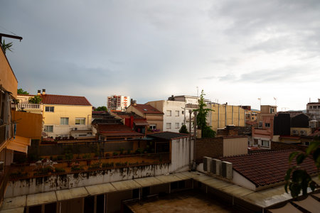 Residential buildings with terraces and rooftops form an urban landscape under a cloudy sky, hinting at an impending change in weatherの写真素材