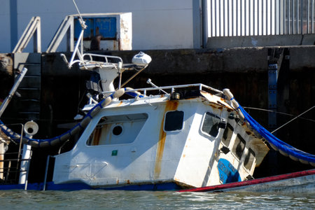 Fishing vessel partially submerged in a harbor, depicting a maritime accident scene with potential...