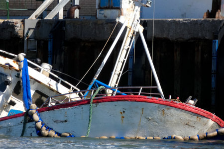 Fishing vessel partially submerged in a harbor, depicting a maritime accident scene with potential...