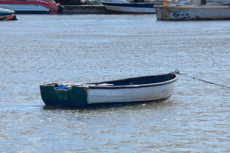 Small blue and white fishing boat resting on wet sand, surrounded by debris
