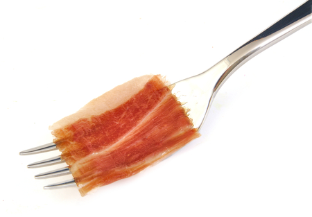 Spanish serrano ham slice on metal forkの写真素材
