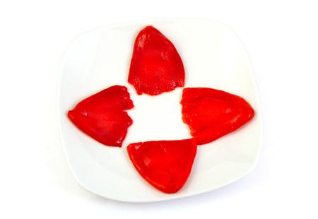 Four roasted red peppers in olive oil on a white dishの写真素材