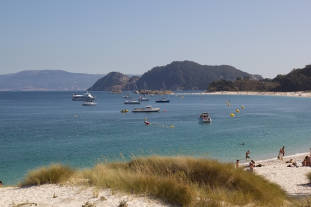 Clear water beach, with boats, and mountainsの写真素材