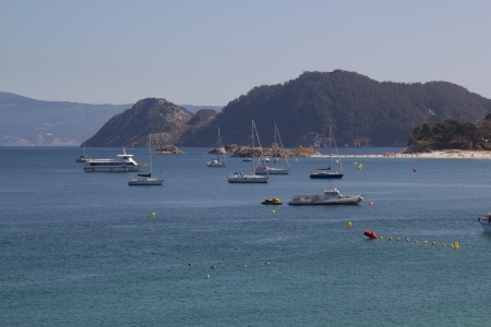 Clear water beach, with boats, and mountainsの写真素材