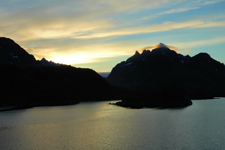 Norwegian fjord surrounded by mountains under the midnight sunの写真素材