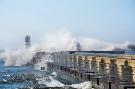 Strong waves hitting the breakwater and the lighthouseの写真素材