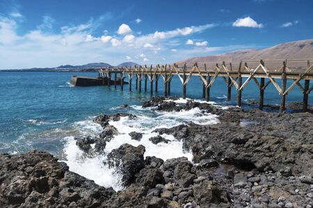 wooden bridge in the canary islands blue sea volcanoes in the background