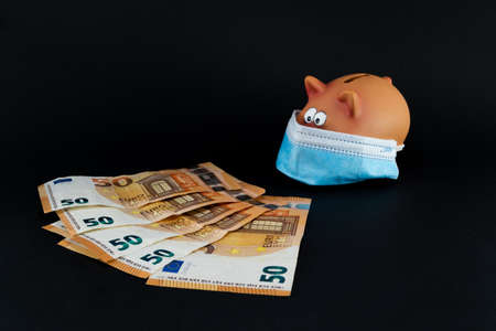 Pig piggy bank figure with sanitary mask in times of Covid in front of euro banknotes