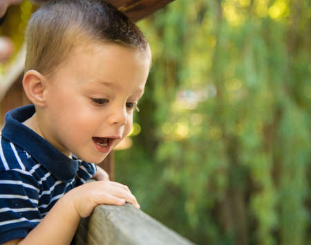 laughing child looking through a wooden railingの写真素材