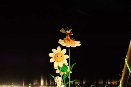 Madrid;Spain;11042009;children's figures: A whimsical scene featuring a cartoonish bee character sitting on a large flower, with a smiling sunflower in the background. The setting is dark, highlighting the colorsの写真素材