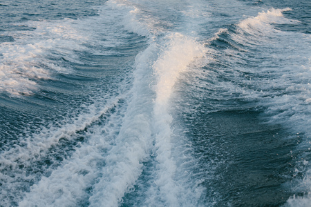 Foamy waves from motor boat on calm sea surface on sunny day. の写真素材