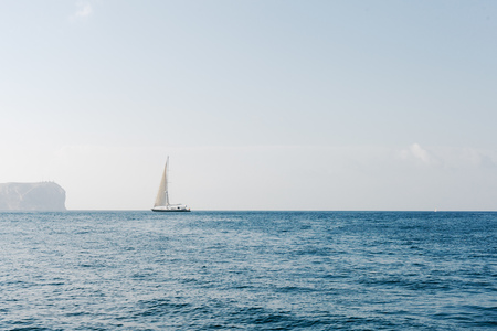 Small yacht sailing in calm sea on sunny day. の写真素材