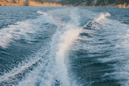 Foamy backwash from boat not far from coast on sunny day.