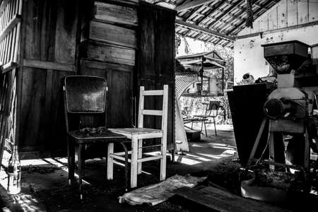 Abandoned pile of paraphernalia (wardrobe, chairs, machines and so forth) at a shed [Black and...