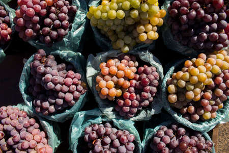 Bundle of white and red / purple / black grapes all placed at a market with vivid colors and healthy...