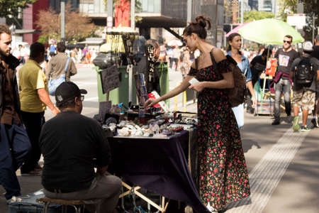 SÃ£o Paulo / SÃ£o Paulo / Brazil - 08 19 2018: Pretty young woman with flower dress buying mystical things at a street sellerのeditorial素材