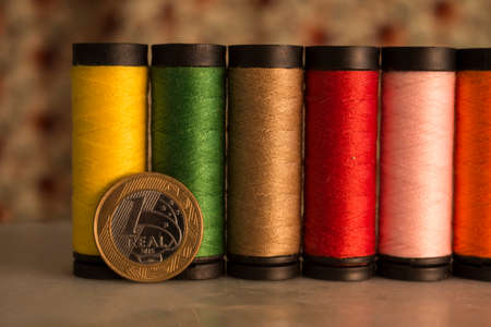 One Real (brazilian currency) with small multicolored threads behind it