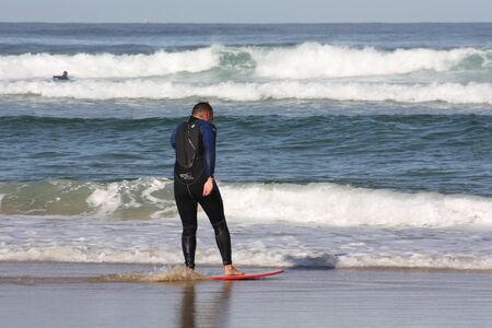 Man in wetsuit does skimboarding on the Atlantic Ocean