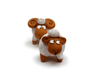 Two white and brown ceramic sheep figurine isolated on white background close upの写真素材