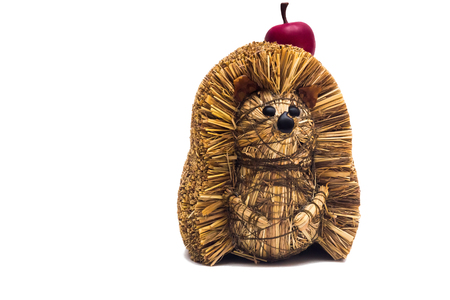 Handmade hedgehog made of hay with artificial apple isolated on white backgroundの写真素材