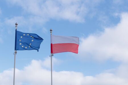 European and Poland flags next to each other waving in the wind against blue sky with cloudsの写真素材