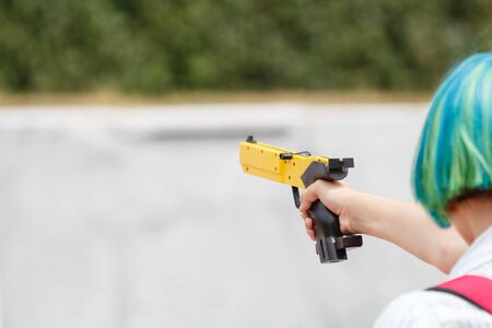 Girl with a yellow laser sport gun aims closeupの写真素材