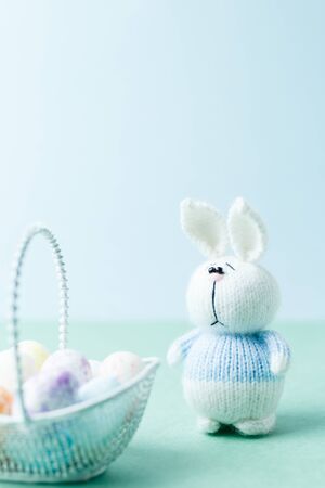 Easter concept. Knitted bunny staying near basket with eggsの写真素材