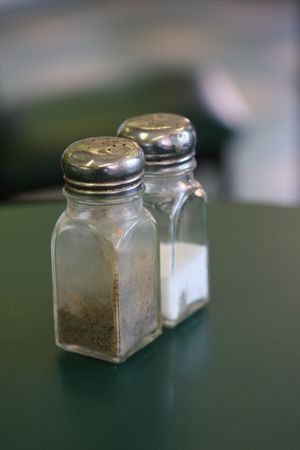 Salt and pepper shaker on a table; shallow DOF on pepper shakerの写真素材