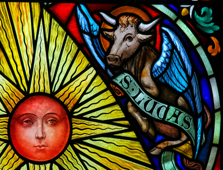 Stained Glass window depicting a Sun and a Bull, symbol of Saint Luke the Evangelist, in the Cathedral of Saint Rumbold in Mechelen, Belgium.のeditorial素材