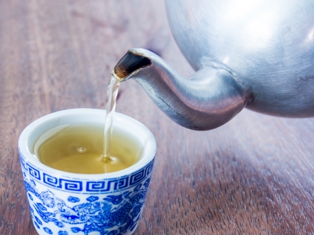 pouring Asian tea into cup on wooden deskの写真素材