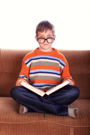 Young child sitting on sofa with bookの写真素材