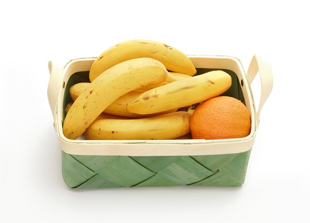 Banana and orange in the wicker basket isolated on the white backgroundの写真素材