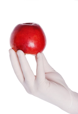 A hand in white rubber glove holding an red apple, isolated on white backgroundの写真素材