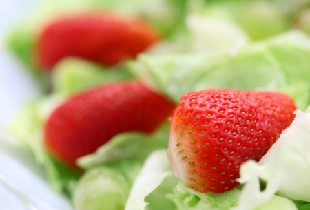 Three strawberries on fresh saladの写真素材