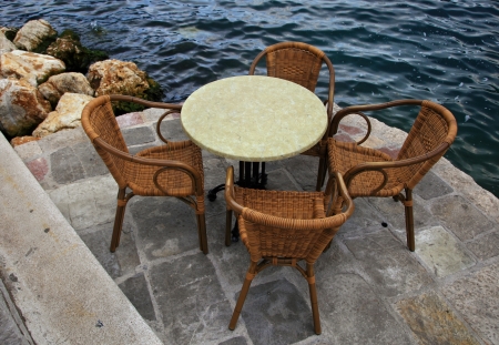 Table and chairs next to seaの写真素材