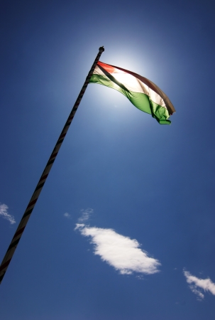 Hungarian tricolour flying in full sunshine against blue skyの写真素材