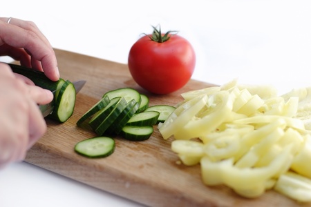 Hand cut gherkin, paprika and tomato on wooden plateの写真素材