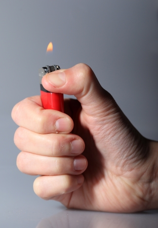 Hand igniting red cigarette lighterの写真素材