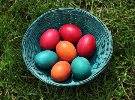 Colorful easter eggs in basket on the groundの写真素材