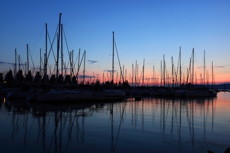 Masted sailboats in a harbor by Lake Balaton at sundownの写真素材