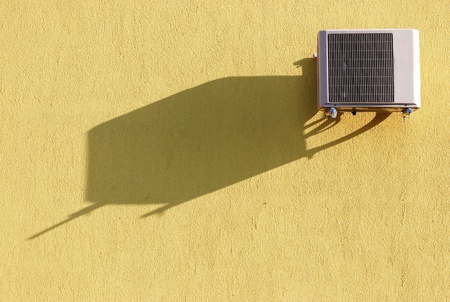 Air conditioner on yellow wall with shadowの写真素材