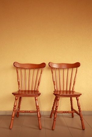 Two wooden chair next to yellow wallの写真素材