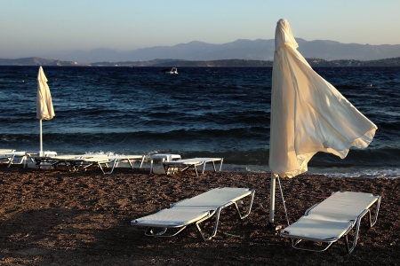 Two umbrella and sunbed at the seashore in windy weatherの写真素材