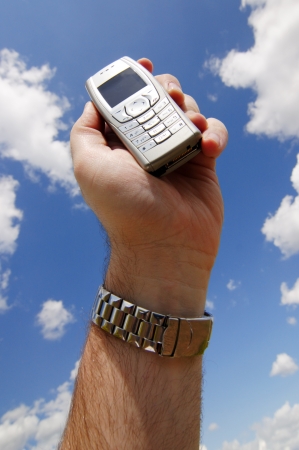 Man s hand lift his mobile phone to the skyの写真素材